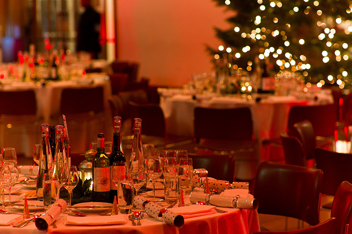 Tables set for Christmas dinner under a warm red glow of light