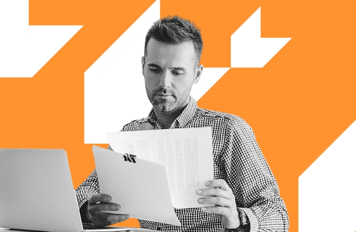 A man reading a contract at a desk with an orange background GC LARGEjpg