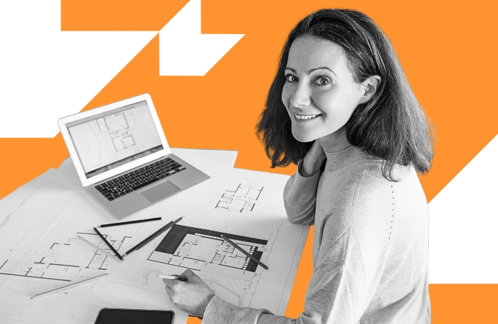Female architect working smiling at camera as she works on technical drawings LARGEjpg