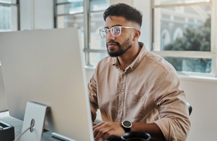 Man wearing glasses and sitting behind a computer in an office GC LARGEjpg