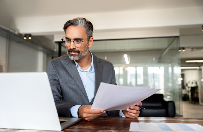 Person looking at laptop and insurance documents 700455jpg