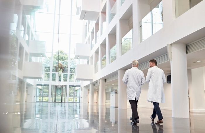 Two doctors walking through a modern hospital with shiny floors and white walls GC LARGEjpg Two doctors walking through a modern hospital with shiny floors and white walls
