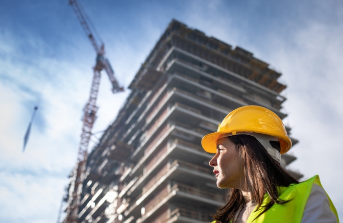 Female architect on a construction site standing in front of a highrise buildingjpg