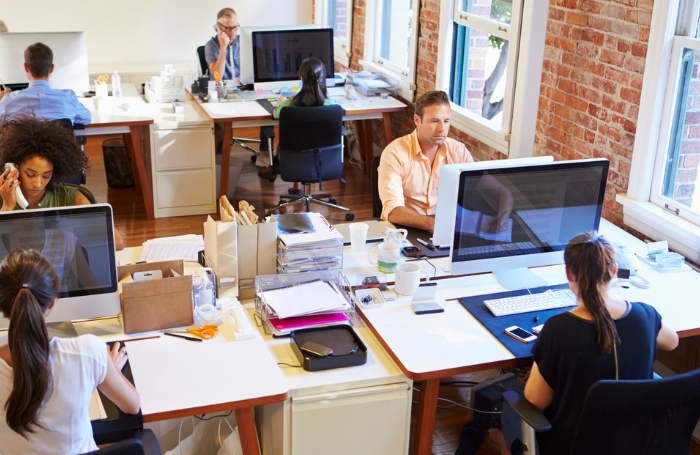 A busy office with both men and women sitting at their desksjpg A busy office with both men and women sitting at their desks
