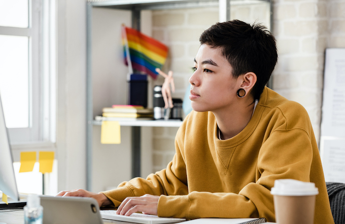An architect in an office working with a Pride flag in the background LARGEjpg