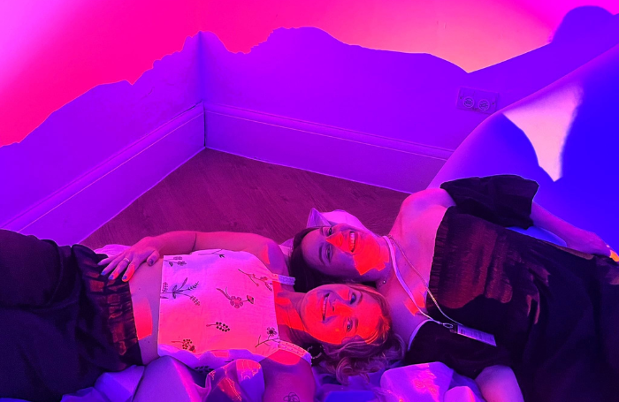 Colourful installations at the Neurodiversity Architecture Network launch partypng Two people lying on miscellaneous foam blocks bathed in purple, pink, and orange lights