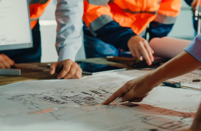 Group of architects pointing and looking at designs on a tablejpg