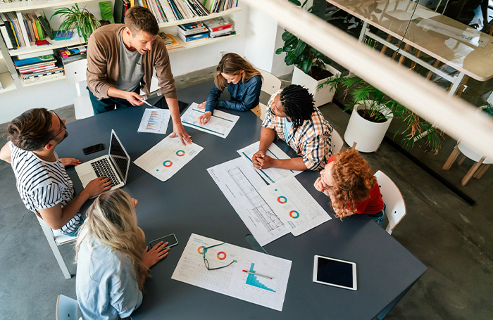 Group of people at a table discussing graphs and data on paperjpg