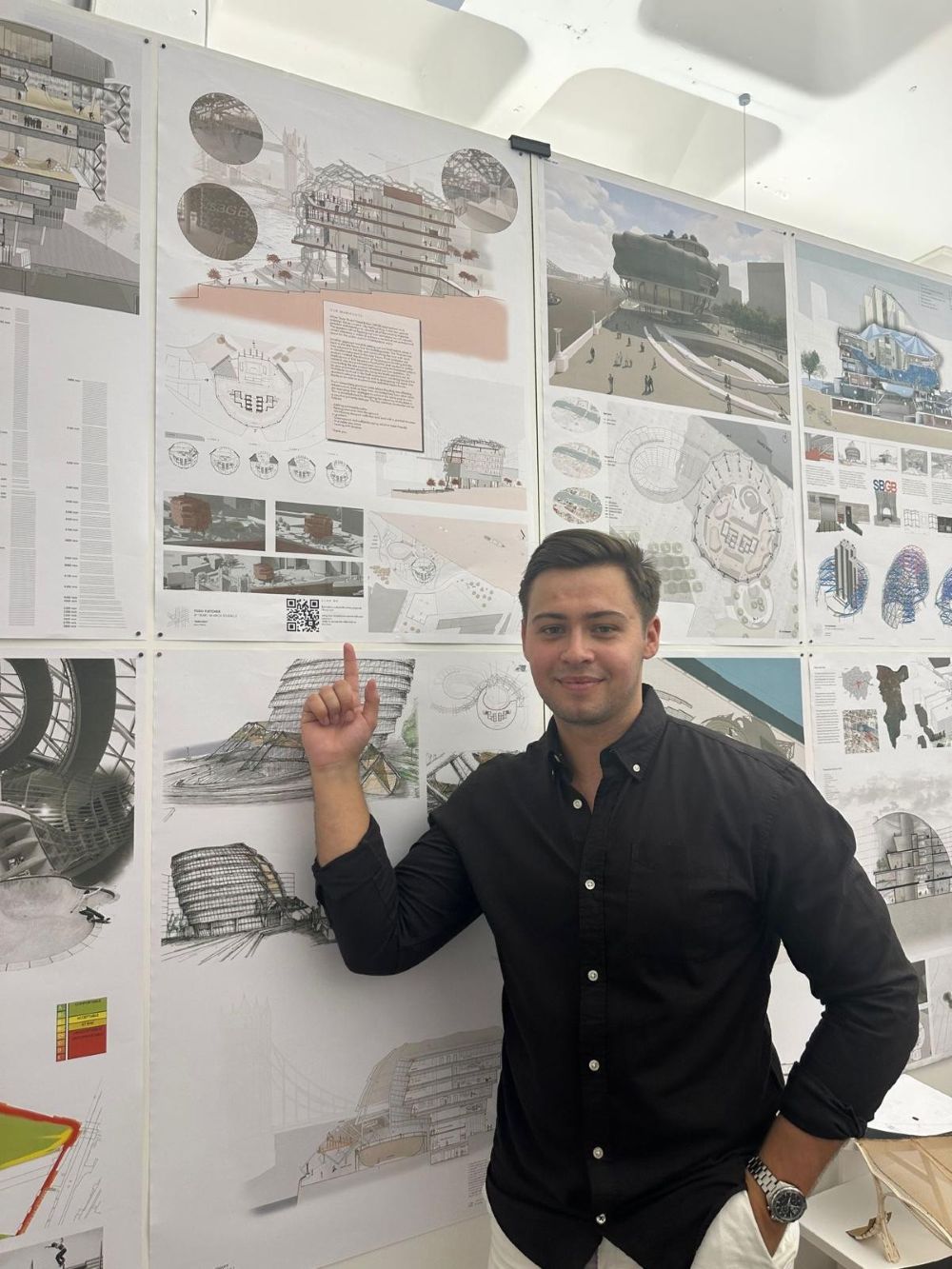 Level 7 architecture apprentice Todd Fletcherjpg Level 7 architecture apprentice Todd Fletcher standing by a wall covered in project work, pointing