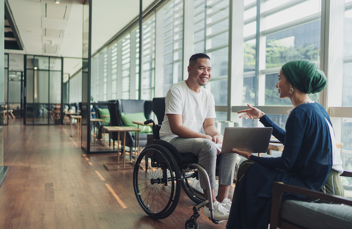 Man in wheelchair chatting to a woman in a buildingjpg