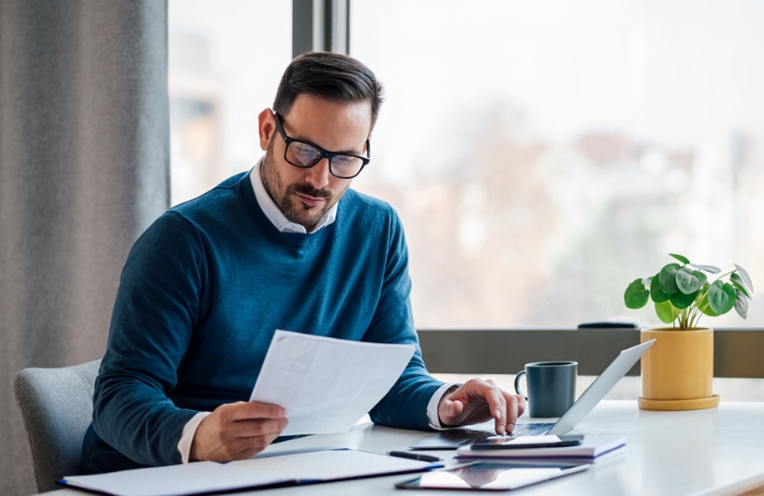 Man waering glasses sitting behind a desk and reviewing documentsjpg