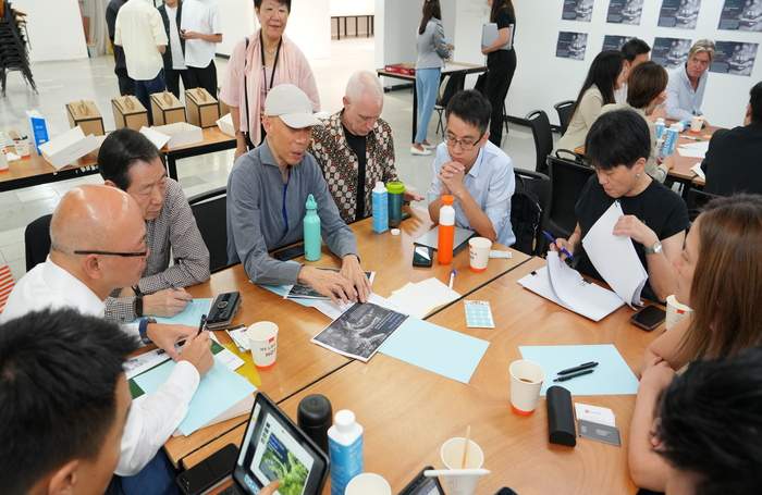 People discussing around a work desk with papers and laptopsjpg