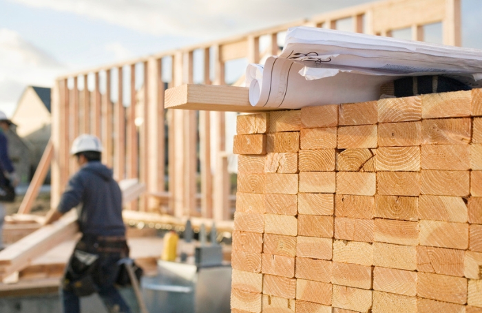 Piled up pieces of timber on a building site GC LARGEjpg pile of stacked timber boards in foreground of construction site.