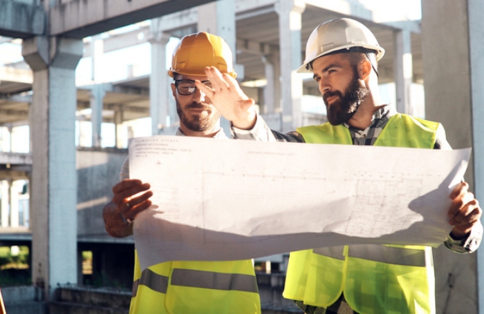 Two architects on site discussing a desing wearing helmetsjpg
