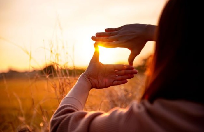 woman framing the sunset with her handsbody700x455jpg
