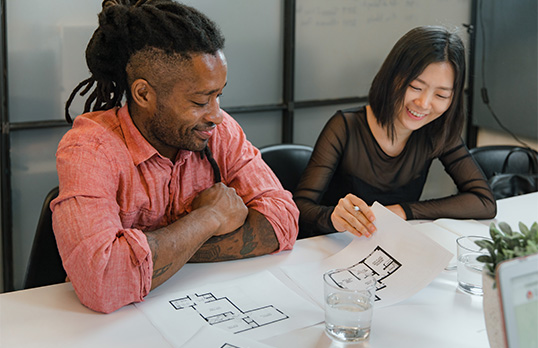 Two architects laughing and discussing architectural plans.